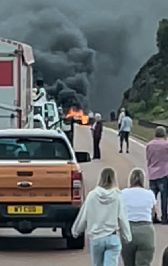 Stunned travellers watch as the pall of smoke from the crash site rises