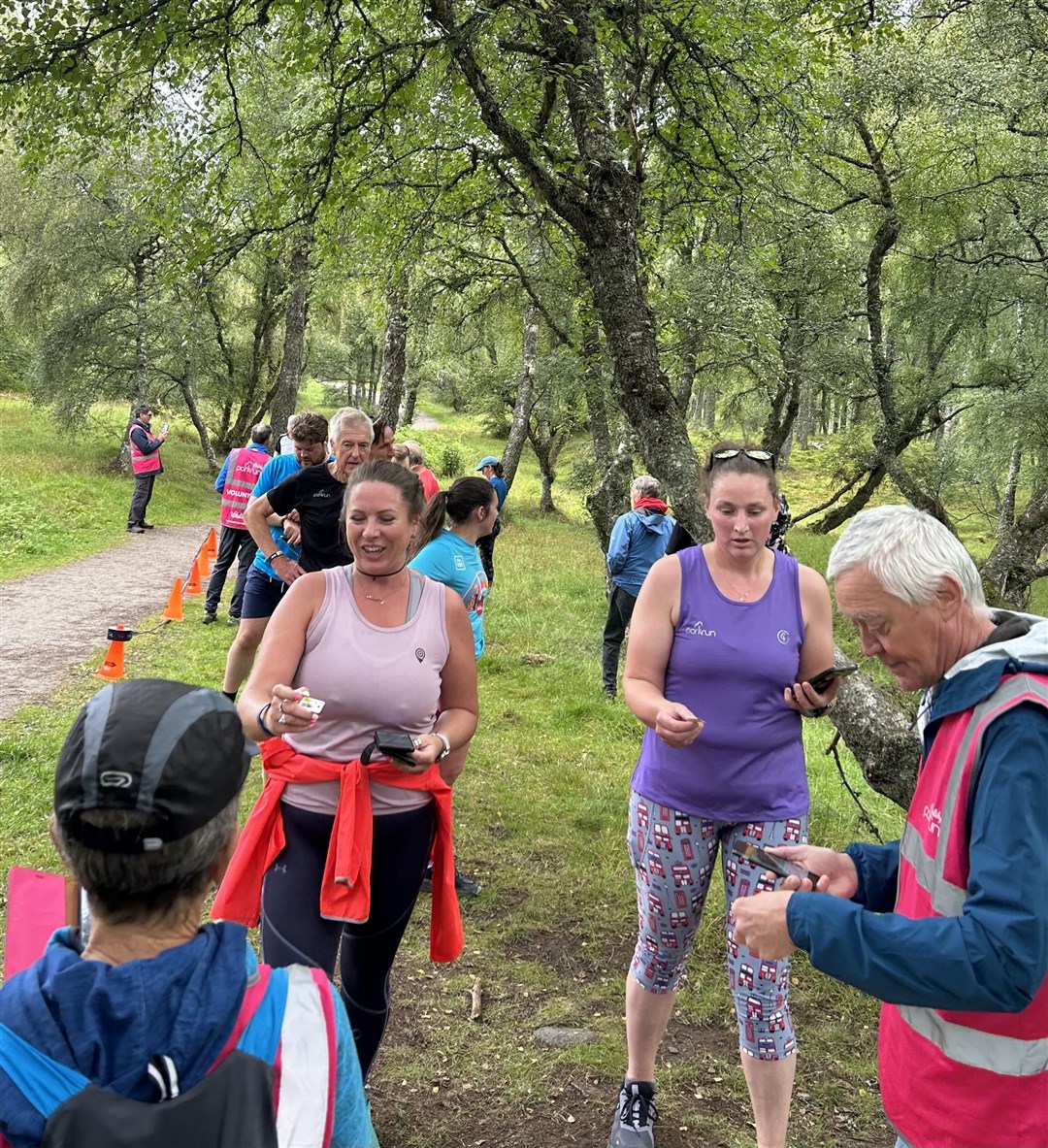 Local parkrunner Ashleigh Robertson and Amanda Harkai in the queue waiting to have their finish tokens and barcodes scanned by regular volunteers Val Machin and Malcolm Hinsley.