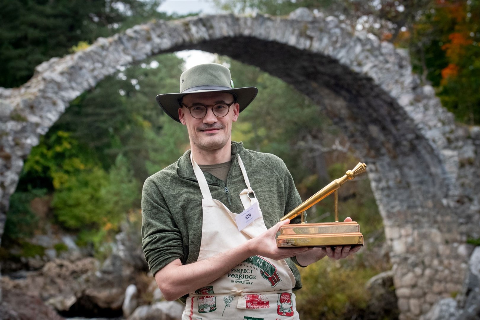 Golden Spurtle winner Chris Ormiston parades his trophy by Carrbridge's legendary packhorse bridge. Picture: Callum Mackay.