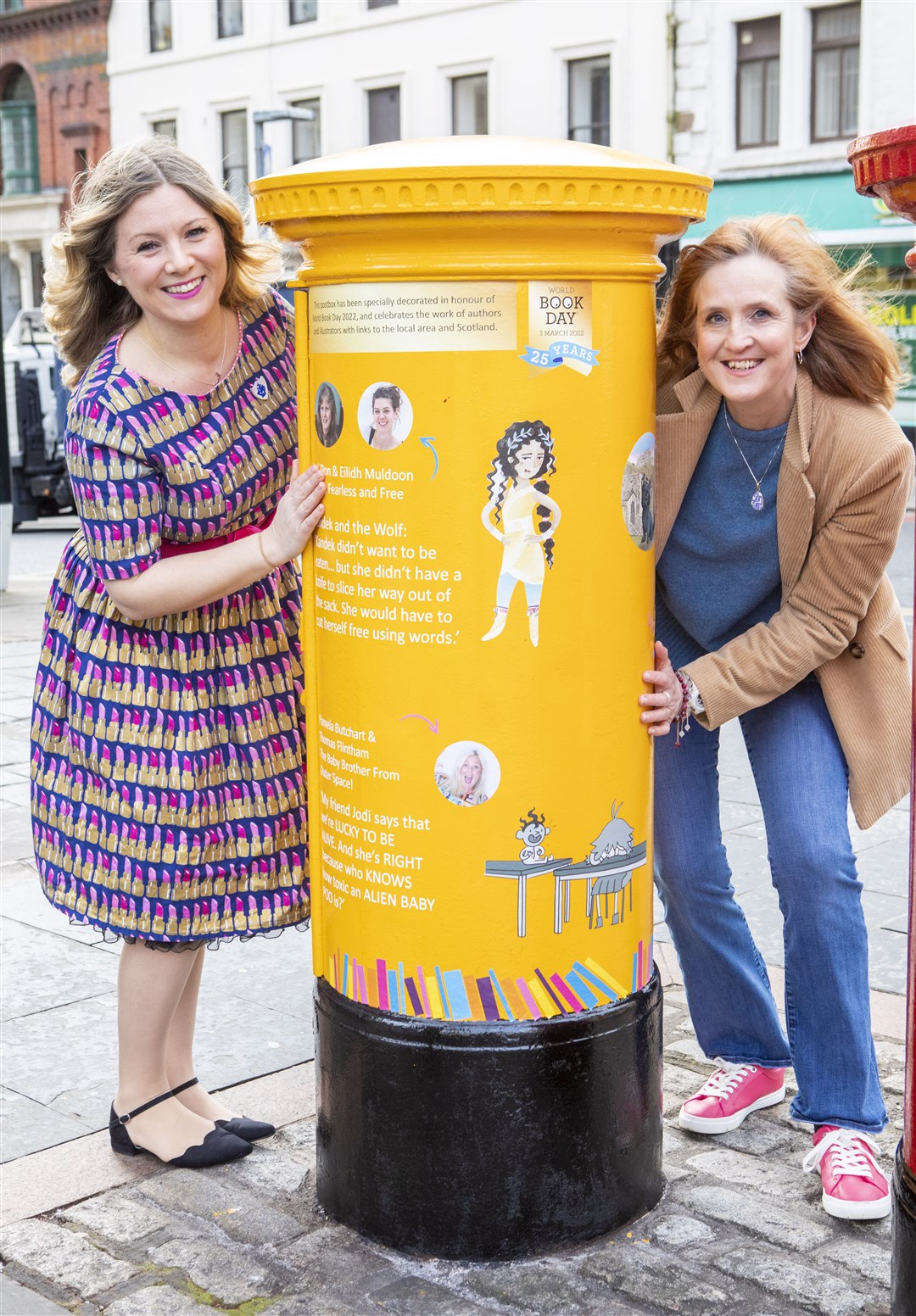 Author Pamela Butchart (left) and Michelle Sloan with a yellow Royal Mail postbox in Dundee, decorated for World Book Day (Royal Mail/PA)