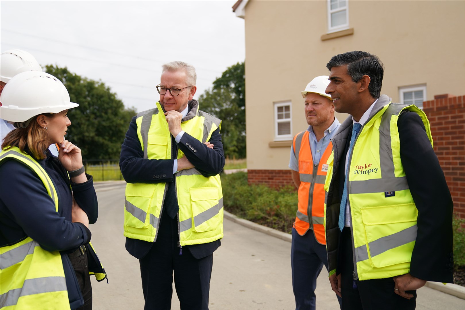 Rishi Sunak and Michael Gove speak to Ella Cole (left), trainee assistant site manager during a visit to the Taylor Wimpey Heather Gardens housing development in Norwich (Joe Giddens/PA)