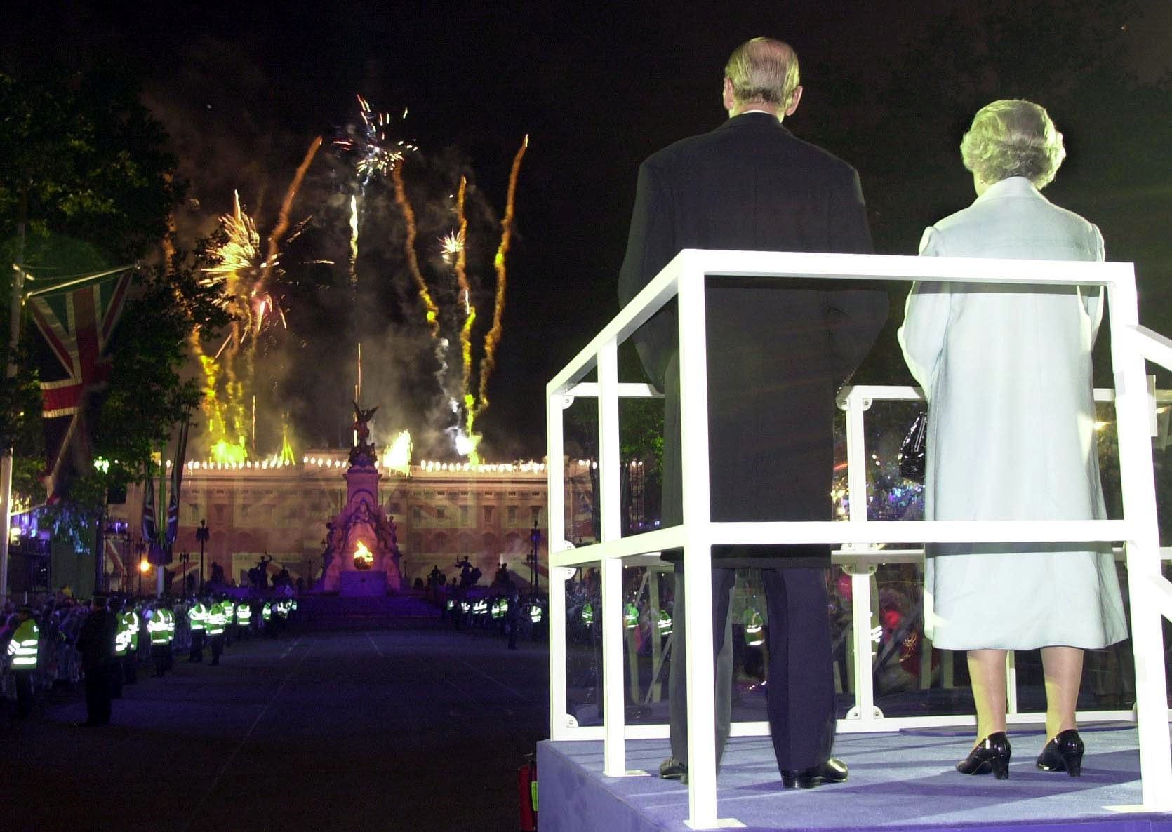 The Queen and Duke of Edinburgh watching fireworks over Buckingham Palace after the monarch lit the central beacon in 2002 (John Stillwell/PA)