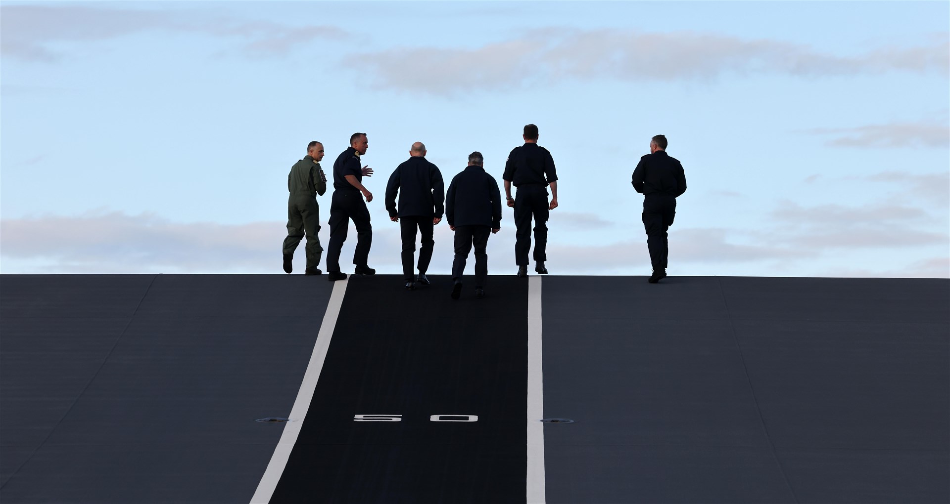 Sir Keir Starmer walks up the F-35 jet take off ramp on the deck of the HMS Prince of Wales (Richard Pohle/PA)