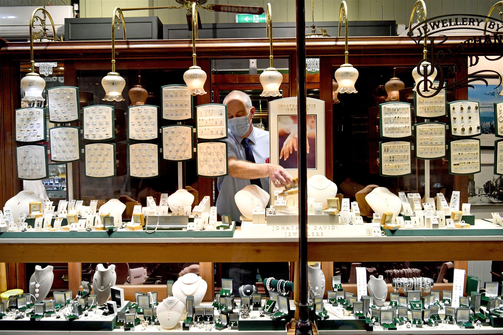 A member of staff removes items of jewellery from the shop window before closing the store ahead of lockdown in Cardiff (Ben Birchall/PA)