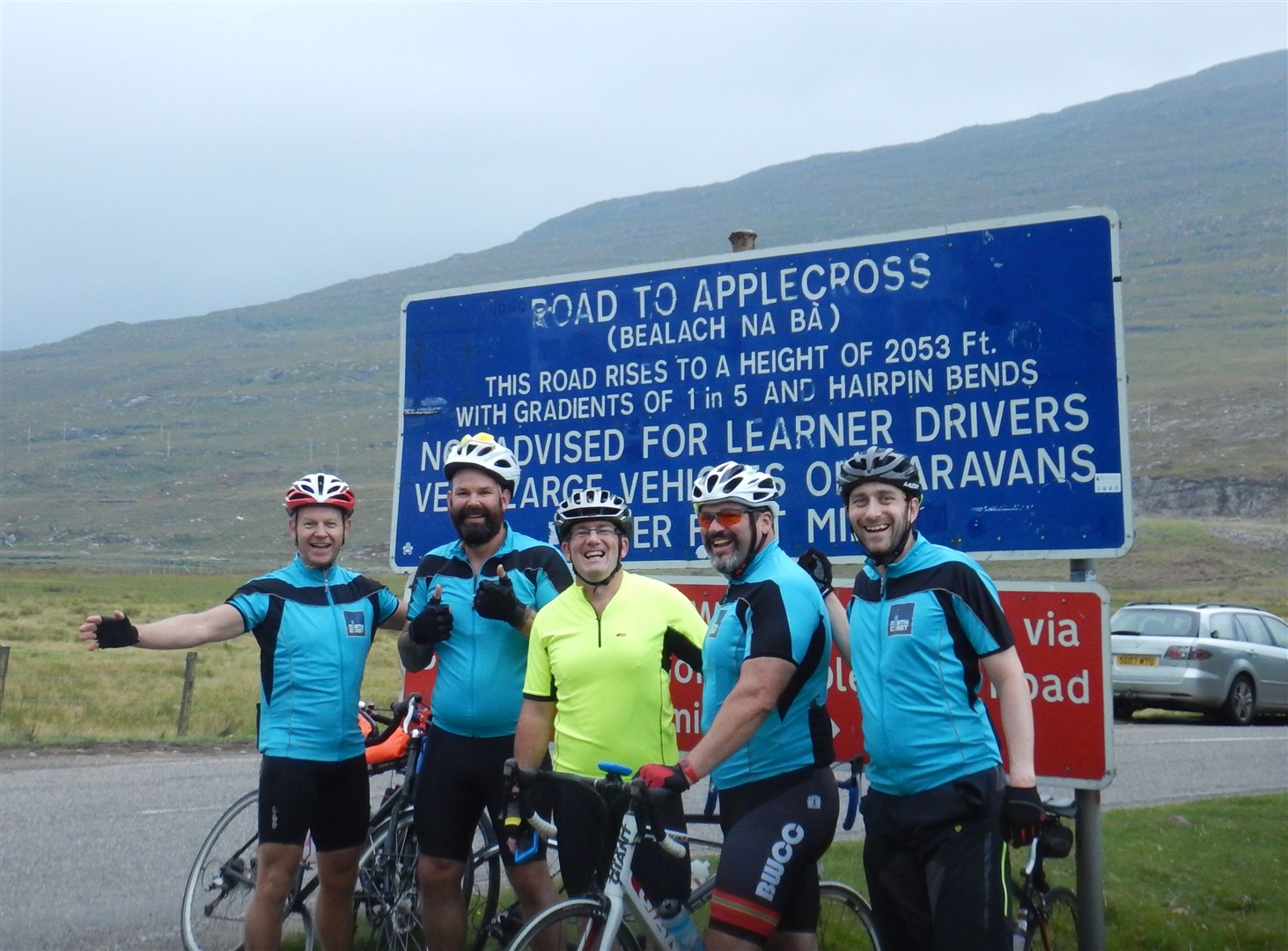The team of five at the bottom of the Bealach na Ba - with the original sign before it was covered in various stickers from NC500 tourists.