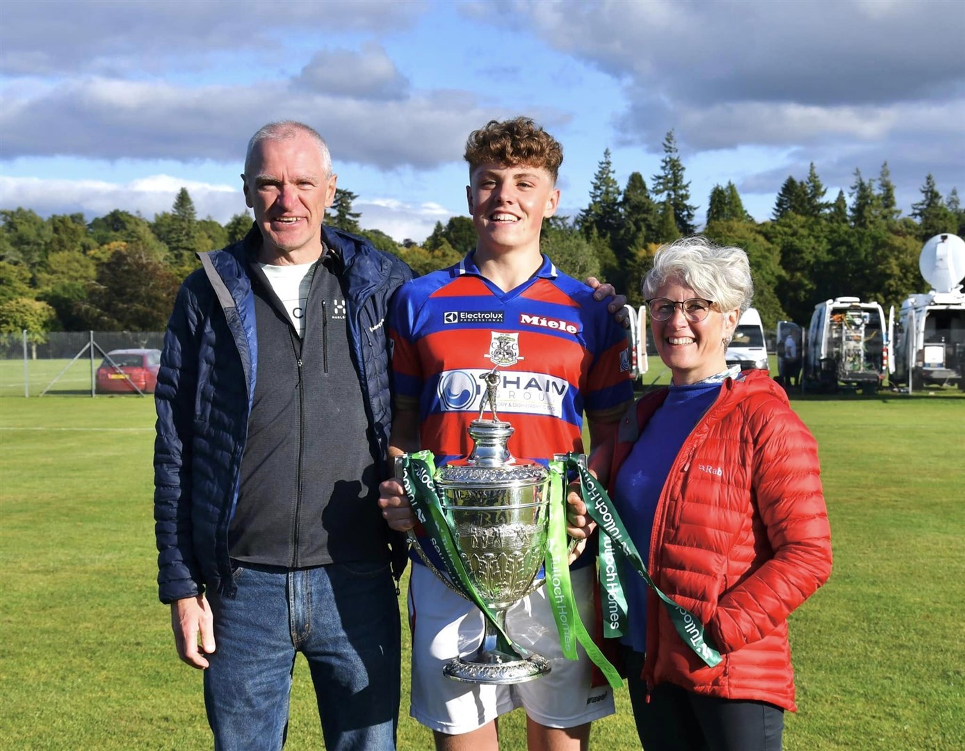 Calum shows off the Camanachd Cup with his proud parents Iain and Ann.