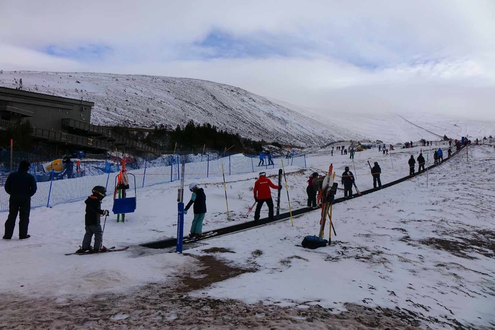 Novices using the magic carpet on the lower beginners' slope by the Day Lodge at Cairngorm Mountain.