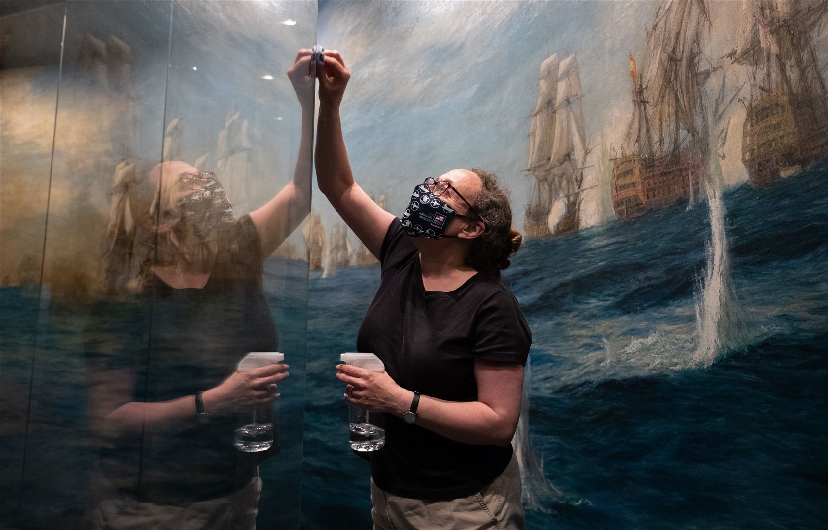 Alison Firth, curator of art at the National Museum of the Royal Navy, cleans the glass window in front of WL Wyllie’s Panorama of the Battle of Trafalgar (Andrew Matthews/PA)
