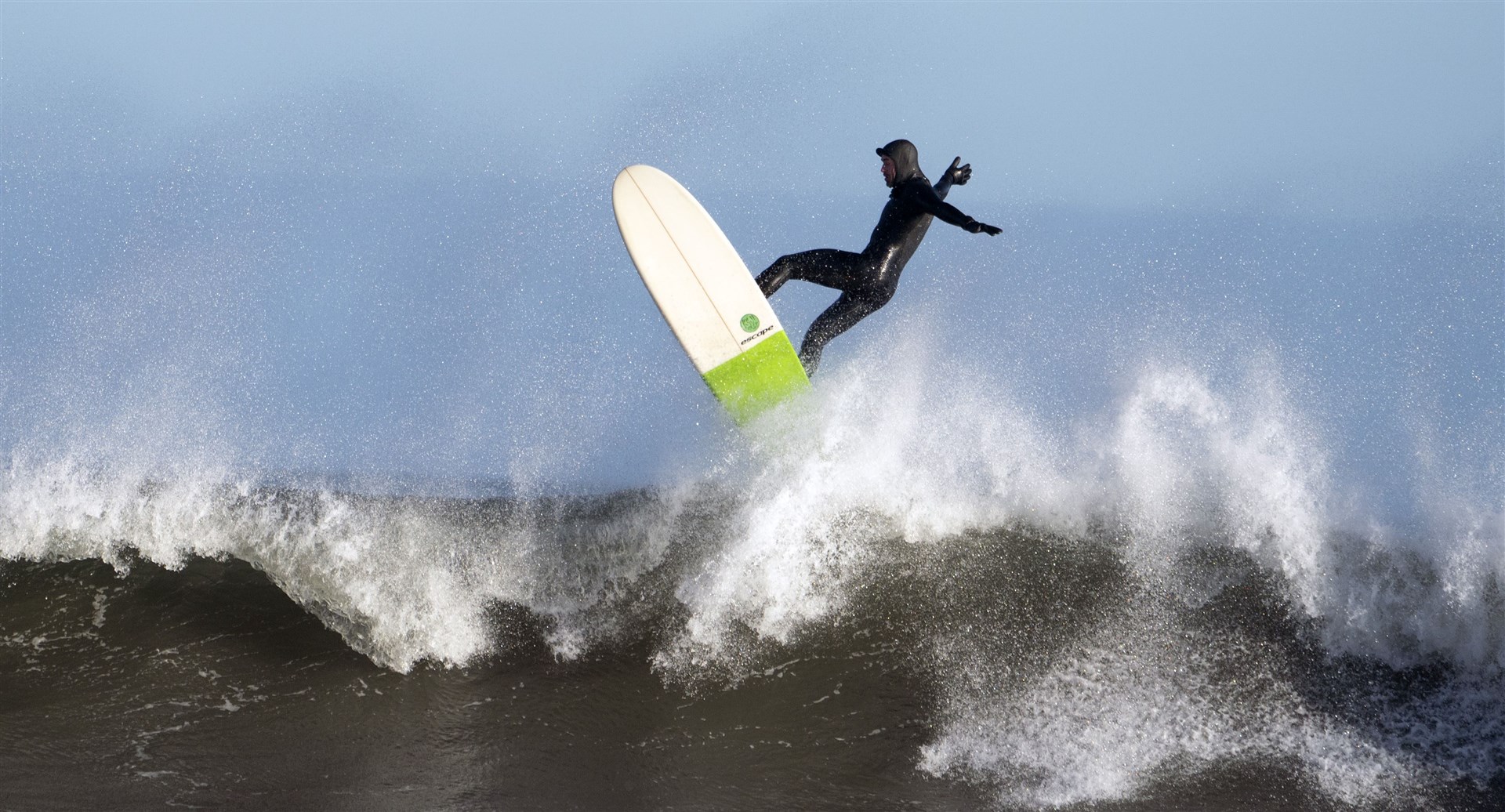 A surfer rides a wave in rough seas off Tynemouth (Owen Humphreys/PA)