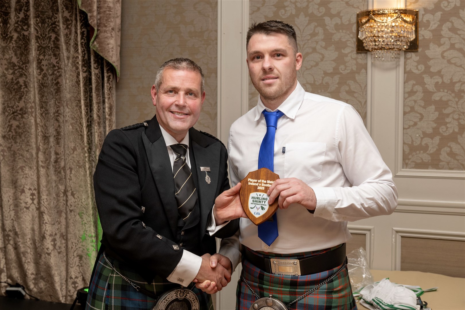 Scotland's Man of the Match Steven Macdonald receives his award from Camanachd Association President Steven Mackenzie at the after match reception. Ireland v Scotland shinty / hurling international, played at Pairc Esler, Newry.