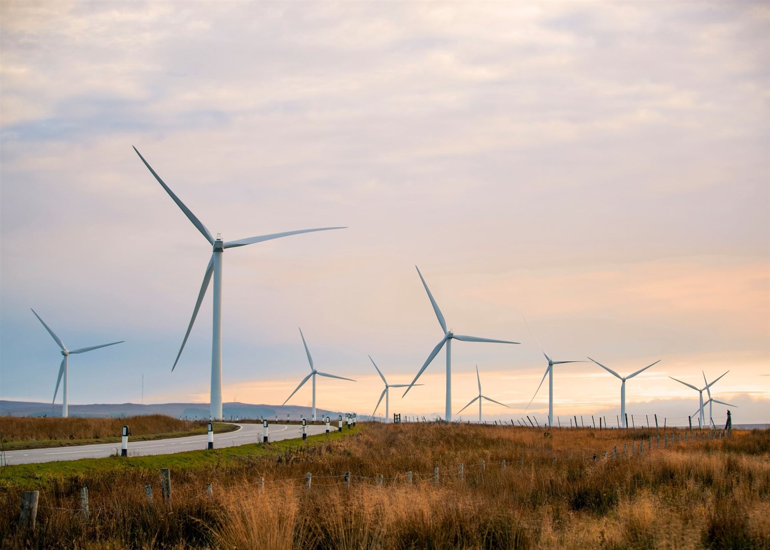 A sunset in the Scottish highlands with renewable energy wind turbines far into the horizon