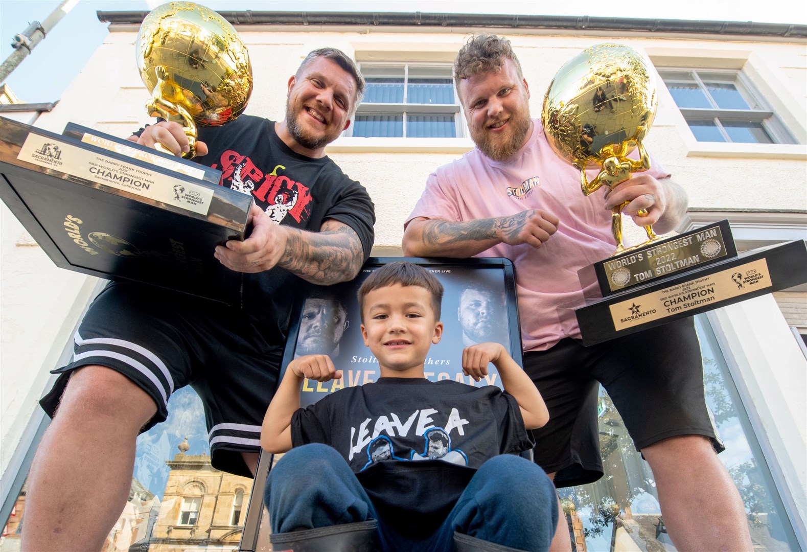 Luke and Tom Stoltman with Jayden Timoney outside the shop. Picture: Callum Mackay..