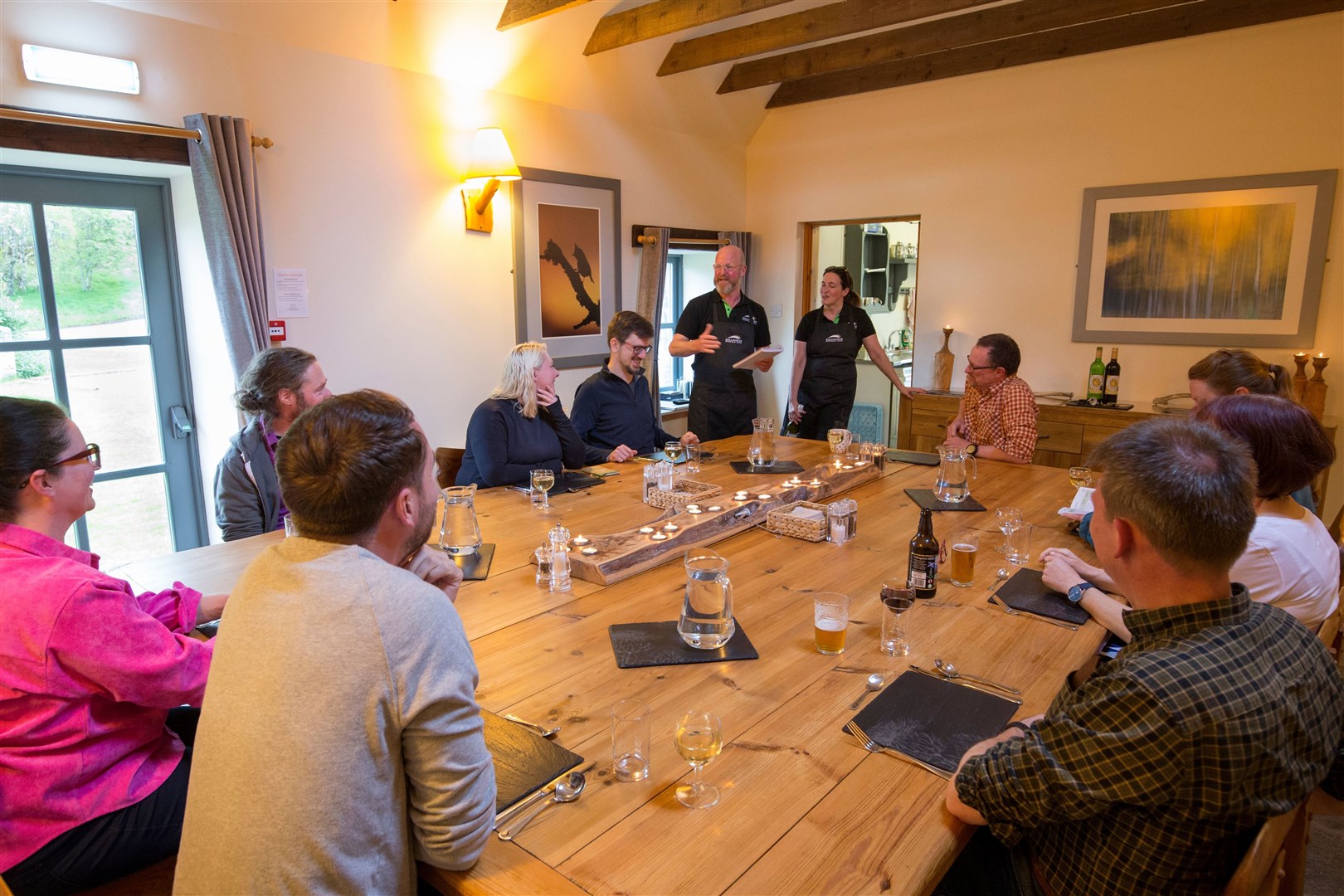 SCOTLAND: The Big Picture rewilding journey group at dining table with Ballintean catering team, Brian Munro and Wendy Sylvester, Cairngorms National Park, Scotland.