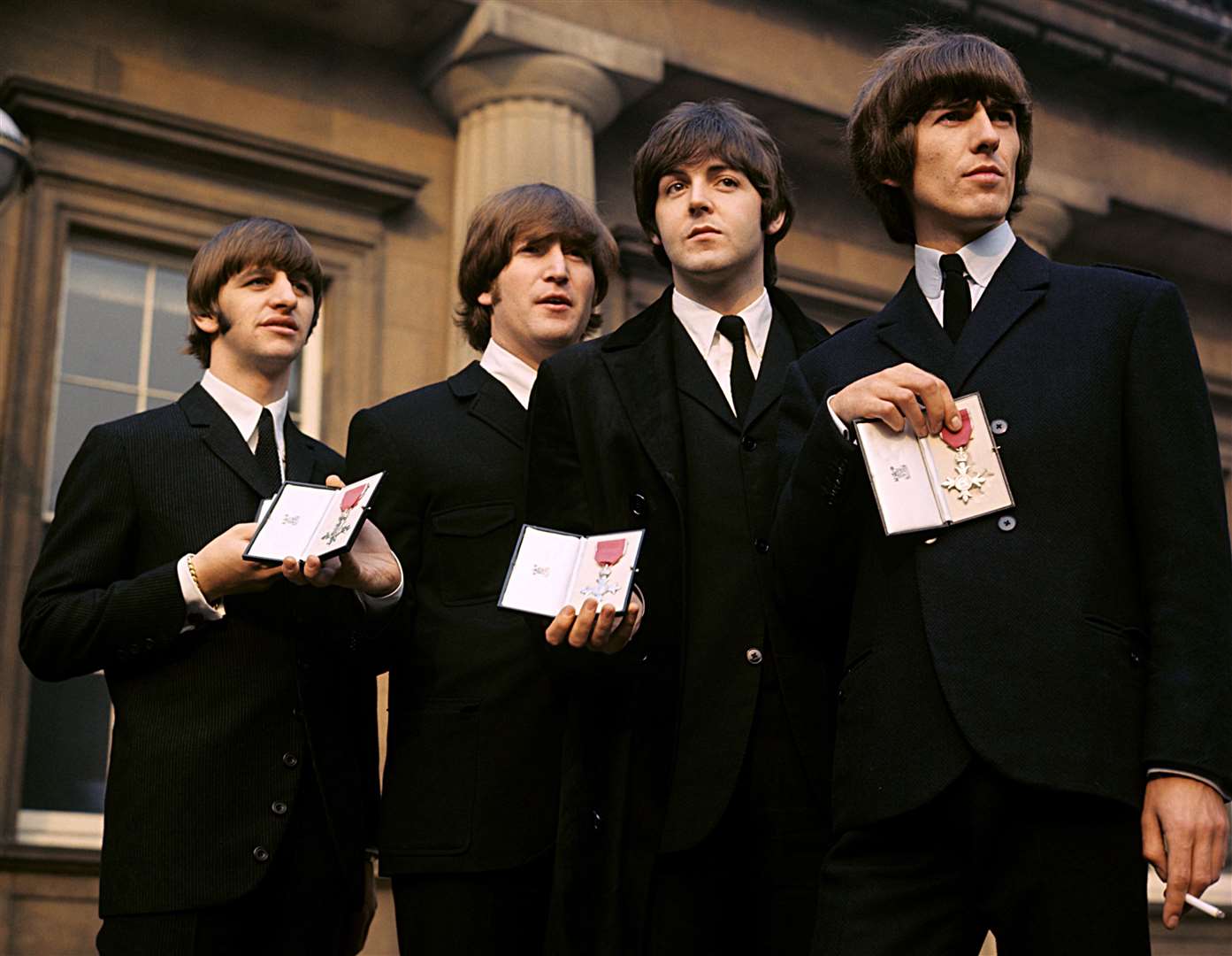 The Beatles showing their MBE Insignias in the forecourt of Buckingham Palace in 1965 (PA)