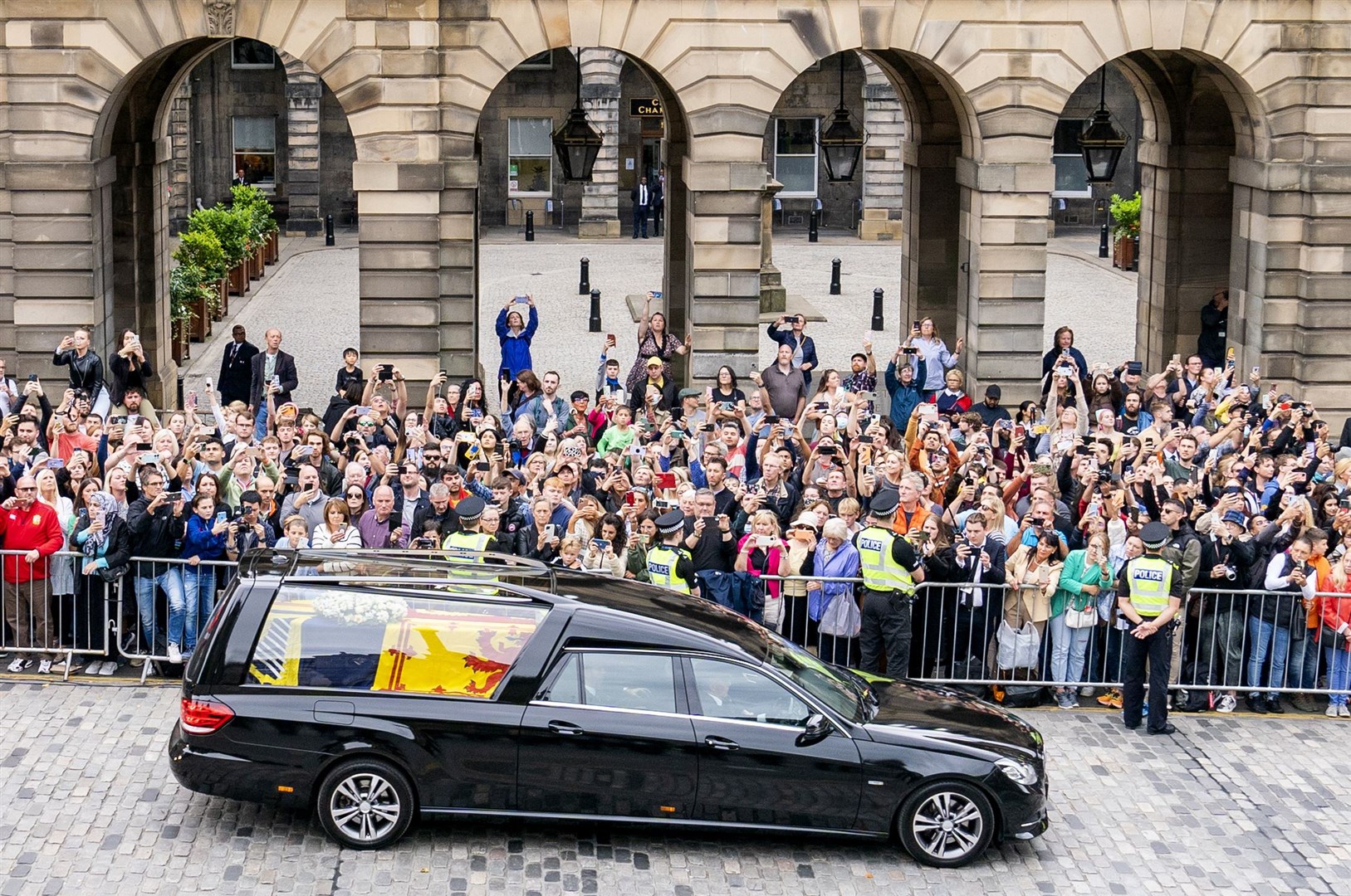 The hearse carrying the coffin of the Queen, draped with the Royal Standard of Scotland, passes down the Royal Mile (Jane Barlow/PA)