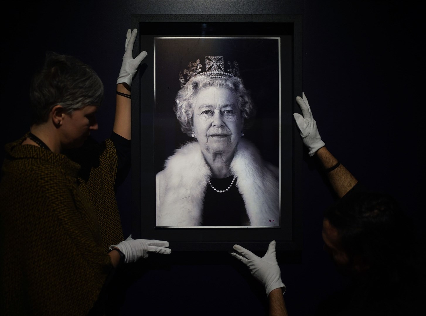 One of many events celebrating the Platinum Jubilee was the Life Through A Royal Lens exhibition at Kensington Palace. Here, conservators handle a lenticular print, Queen Elizabeth II, In Lightness of Being, taken by light artist Chris Levine in 2004 (Yui Mok/PA)