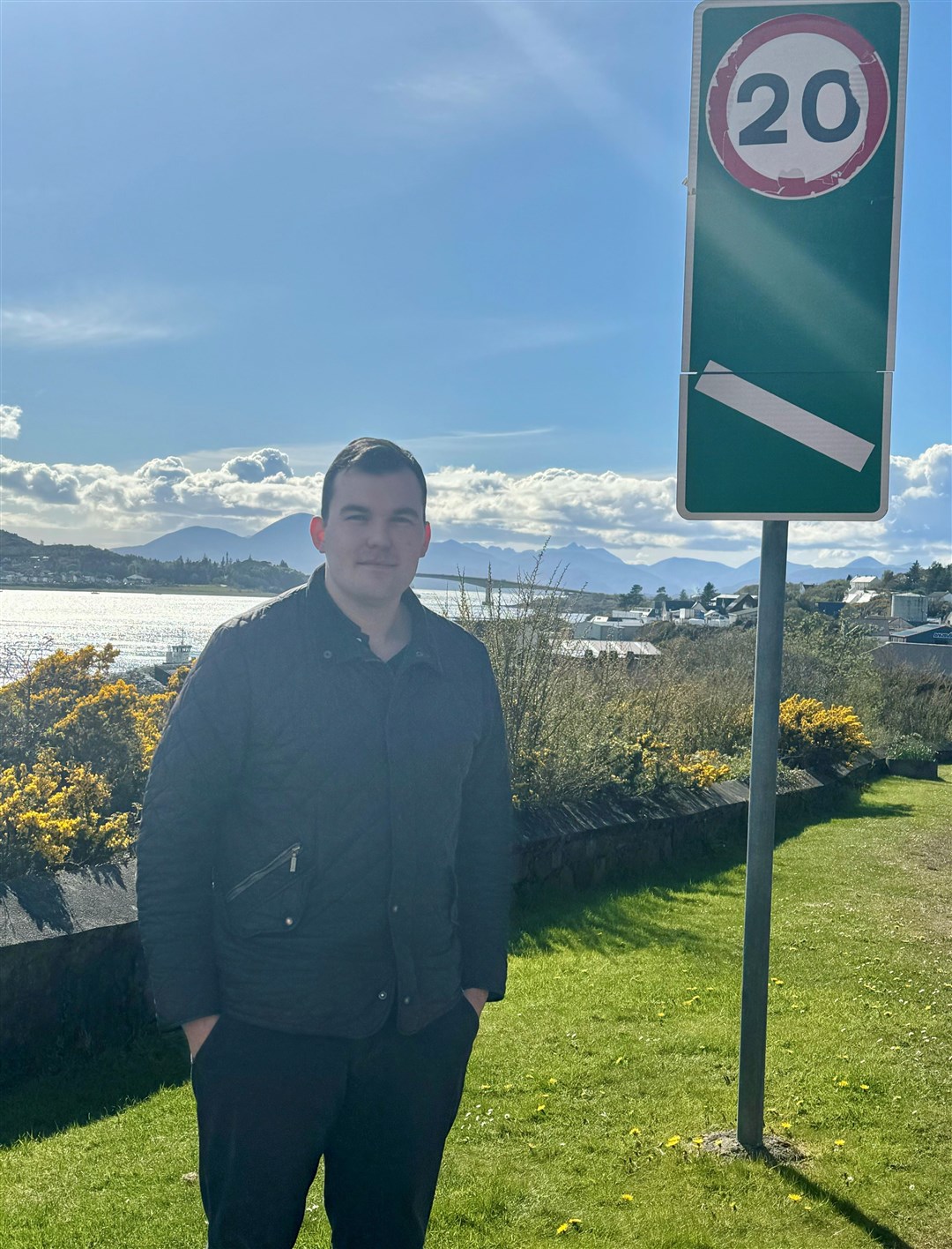 Cllr Ruraidh Stewart next to one of the 20mph limit signs entering Kyle of Lochalsh.