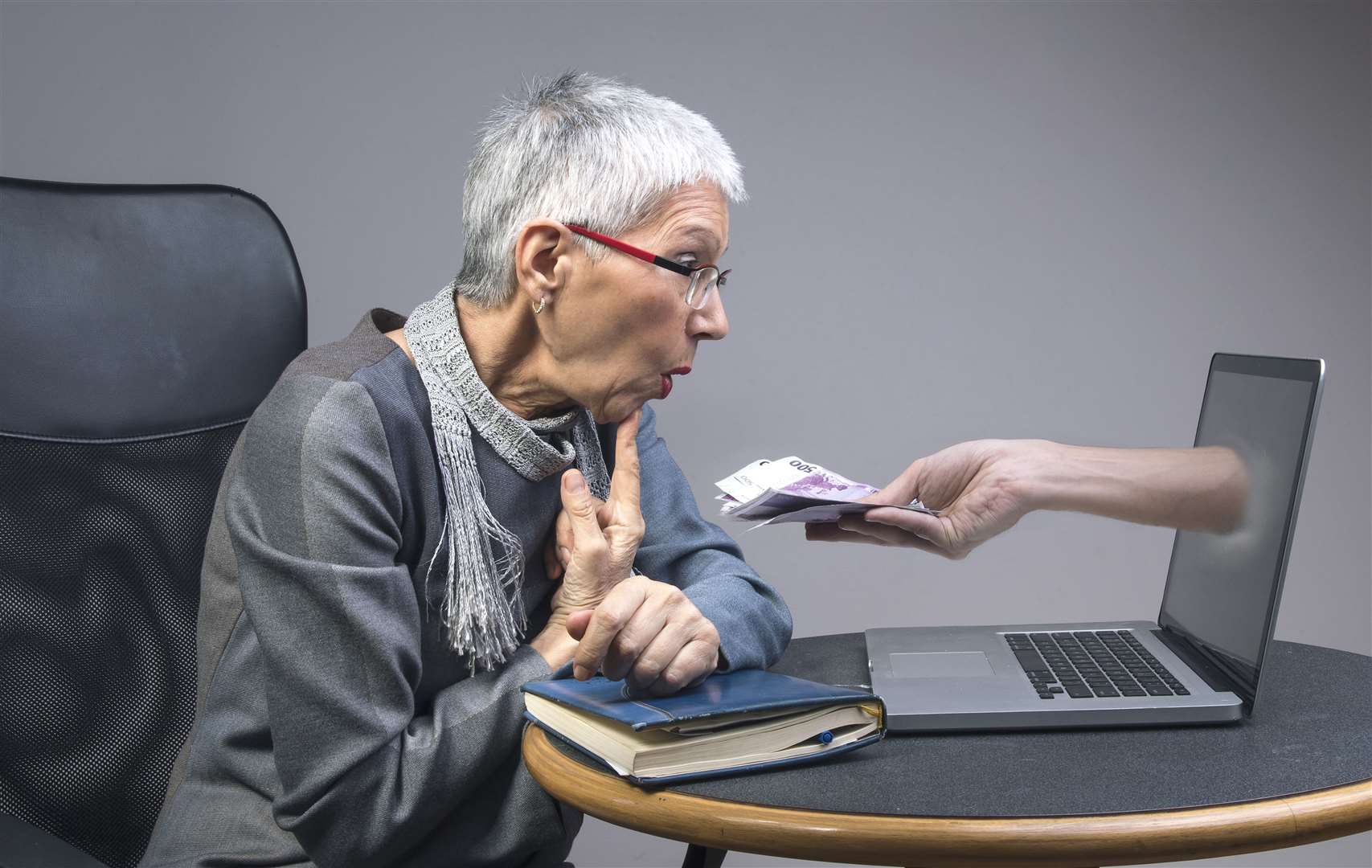 Gullible senior old lady being lured into an online scam that promises easy money, money fraud concept