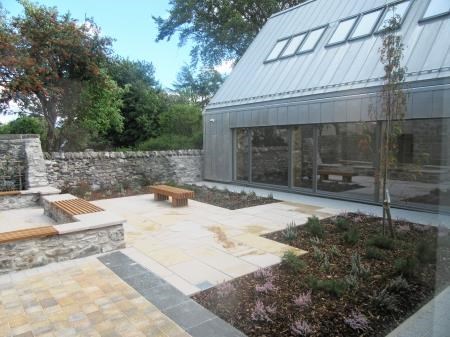 The steel-clad annexe casts a modern shadow on the restored drystane wall in the new courtyard.