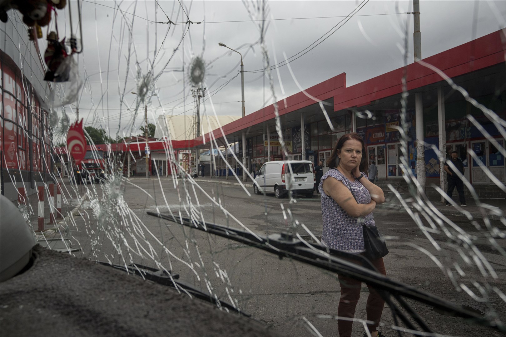 A woman looks at a trolleybus damaged by Russian shelling at Barabashovo market in Kharkiv, Ukraine (Evgeniy Maloletka/AP)