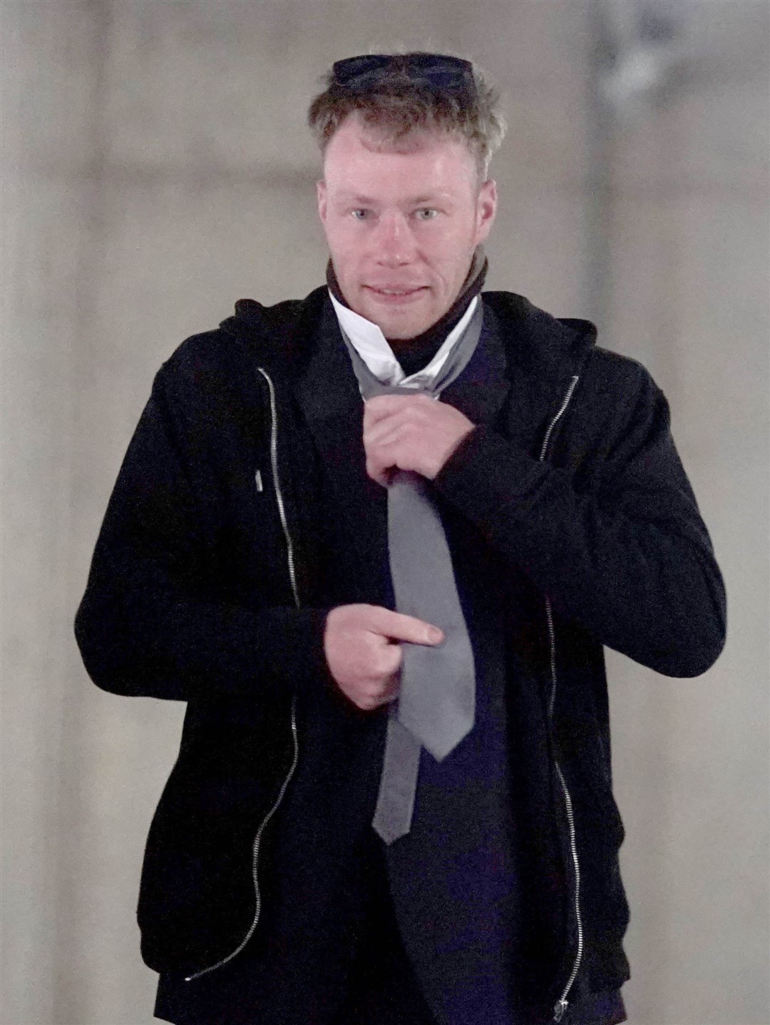 Adam Carruthers, 32, adjusts his clothing as he arrives to attend Newcastle Crown Court where he is accused of criminal damage after the felling of the Sycamore Gap tree (PA)