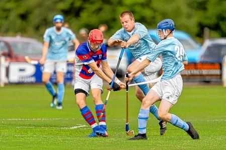 Kingussie's Alexander Michie fends off Ali MacLennan and Calum Mackinnon.